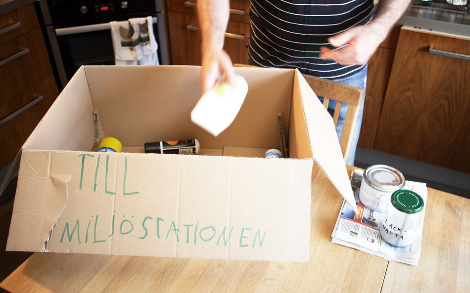 En man packar en kartong med farligt avfall som ska till miljöstationen.